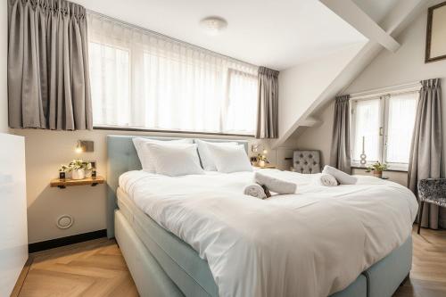 a bedroom with a large bed with white sheets and windows at Harmony Room At The Best Location in Tilburg