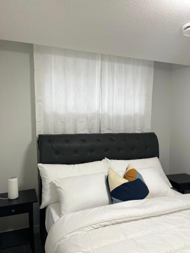 a bed with a black headboard and white pillows at One bedroom private entrance suite in Edmonton