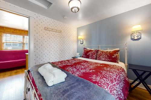 1 dormitorio con cama roja y sofá rojo en Hidden Villa Cottage #1 - The Nautical Cottage, en Cannon Beach