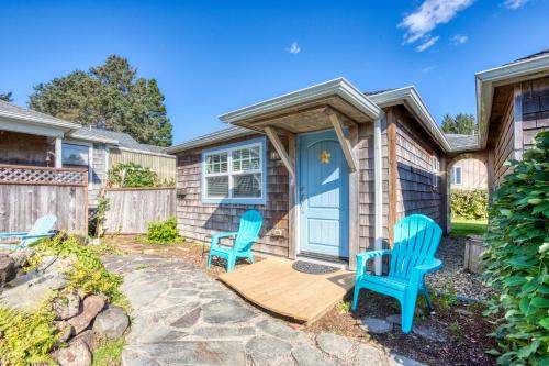 a home with two blue chairs on a patio at Hidden Villa Cottage #4 - The Ocean Cottage in Cannon Beach
