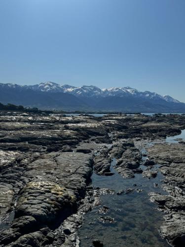a river in a rocky field with mountains in the background at Austin Heights - Kaikoura in Kaikoura