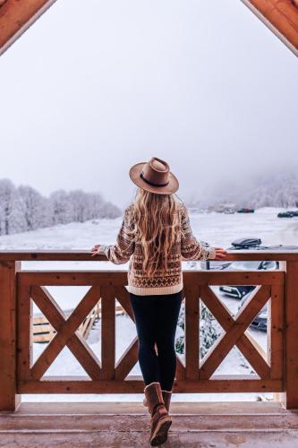 a woman wearing a hat standing on a fence at Domki Osada Zieleniec in Duszniki Zdrój