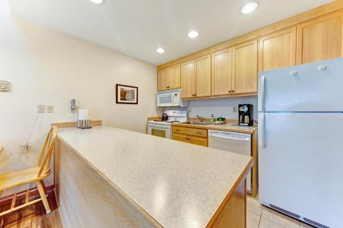 a kitchen with a white refrigerator and wooden cabinets at Embarcadero on the Water #G146 in Newport