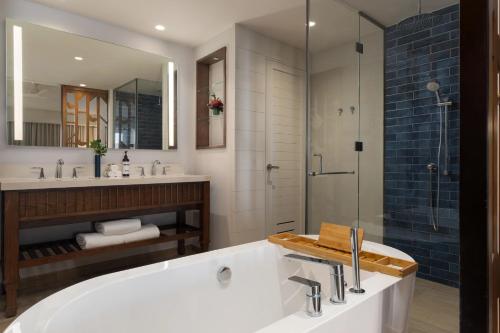 a bathroom with a tub and a glass shower at Dreams Cap Cana Resort & Spa - All Inclusive in Punta Cana