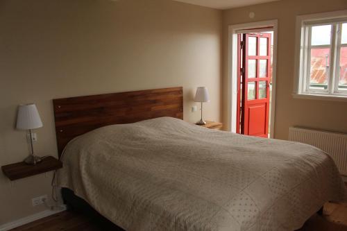 1 dormitorio con 1 cama y puerta roja en Kolkuós Guesthouse en Kolkuós 