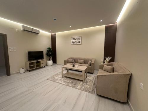 a living room with a couch and a table and a tv at الواجهة in Buraydah