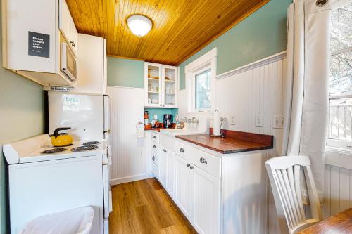 une cuisine avec des appareils blancs et un plafond en bois dans l'établissement Hidden Villa Cottage #3 - The Garden Cottage, à Cannon Beach