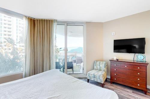 a bedroom with a bed and a television and a chair at Palms of Destin 1307 in Destin