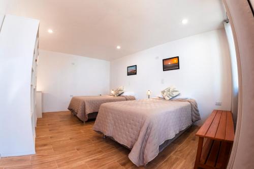 two beds in a room with white walls and wooden floors at Che Lobitos in Lobitos