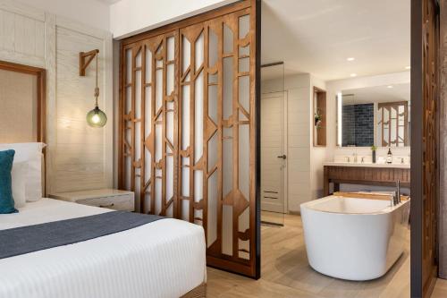 a bedroom with a bed and a tub next to a bathroom at Dreams Cap Cana Resort & Spa - All Inclusive in Punta Cana