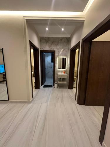 a room with a hallway with wooden floors and a bathroom at الواجهة in Buraydah