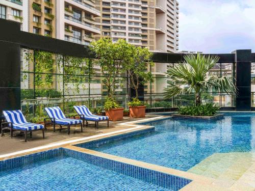 a swimming pool with chairs and a building at Sofitel Mumbai BKC in Mumbai