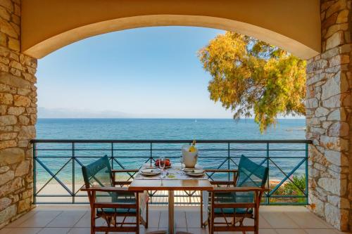 a table on a balcony with a view of the ocean at Grekis Beach Hotel and Apartments in Petalidhion