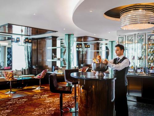 a man standing at a bar in a restaurant at Sofitel Mumbai BKC in Mumbai