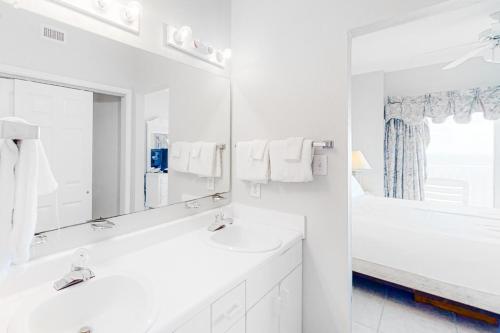 Un baño blanco con dos lavabos y un espejo. en Tidewater 908, en Orange Beach