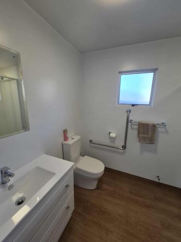 a white bathroom with a toilet and a window at Alexandra Motor Lodge NZ in Alexandra