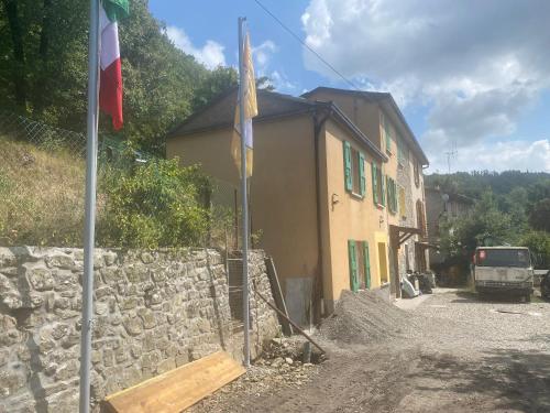 a building with a flag next to a stone wall at La Quercia in San Benedetto Val di Sambro