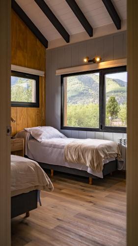 a bedroom with two beds and a large window at 4Puntas Lodge in Lago Meliquina