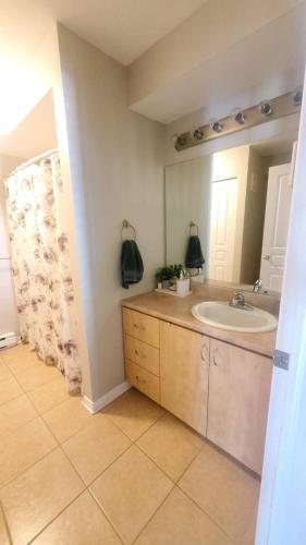 a bathroom with a sink and a mirror at Boho Retreat 3BD Condo Close to Ottawa in Gatineau