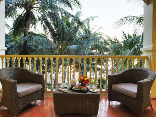 a balcony with two chairs and a table with food on it at La Veranda Resort Phu Quoc - MGallery in Phu Quoc