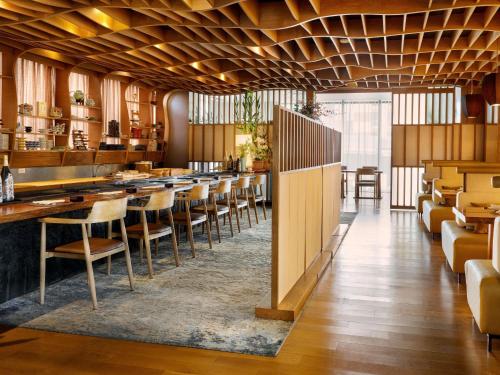 a restaurant with a long bar with chairs and tables at VIE Hotel Bangkok - MGallery Collection in Bangkok