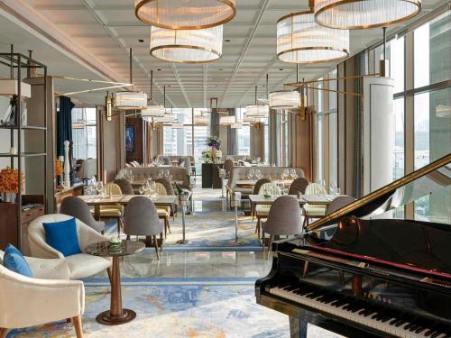 a lobby with a piano and tables and chairs at VIE Hotel Bangkok - MGallery Collection in Bangkok