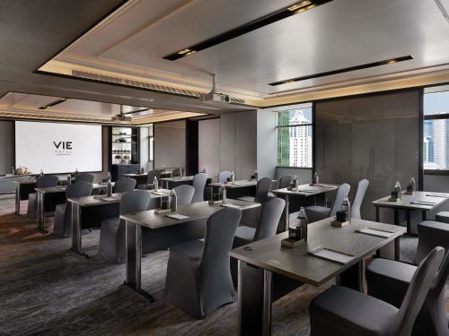 a restaurant with tables and chairs and a screen at VIE Hotel Bangkok - MGallery Collection in Bangkok