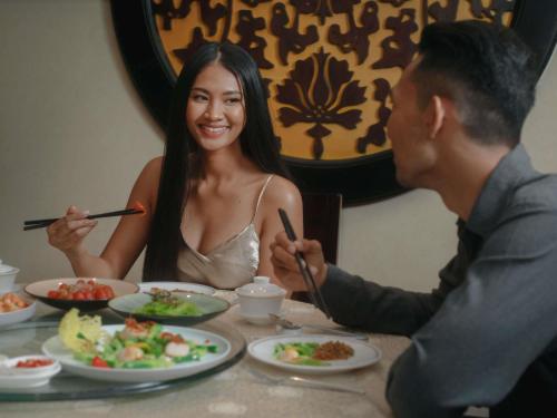 a man and a woman sitting at a table eating food at Sofitel Phnom Penh Phokeethra in Phnom Penh
