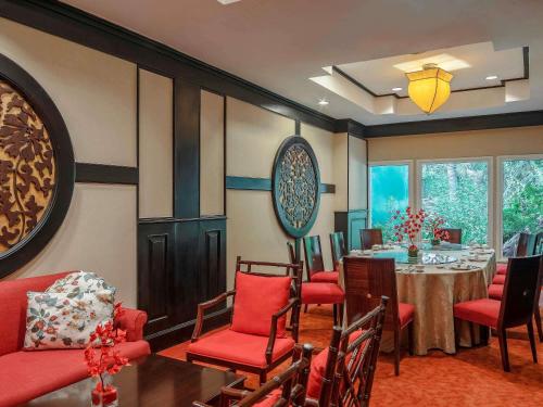 a dining room with a table and red chairs at Sofitel Phnom Penh Phokeethra in Phnom Penh