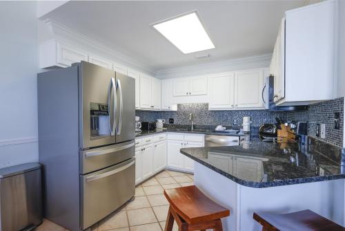 a kitchen with white cabinets and a stainless steel refrigerator at Phoenix VI 61507 in Orange Beach