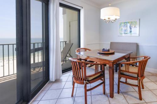 a dining room with a table and chairs and a balcony at Phoenix VI 61507 in Orange Beach