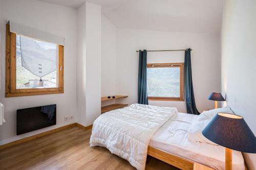 a white bedroom with a bed and a tv at Magnifique Appart Duplex Valthorens in Val Thorens