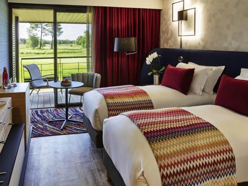a hotel room with two beds and a table at Cabot Hotel Bordeaux - MGallery Collection in Le Pian-Médoc