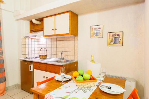 a kitchen with a table with a bowl of fruit on it at Grekis Beach Hotel and Apartments in Petalidhion