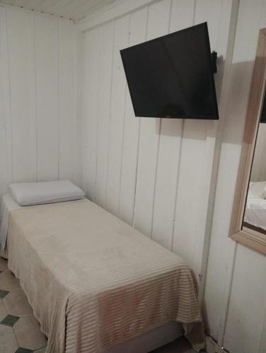 a room with two beds and a flat screen tv at Pousada Do Sol Ilha do Mel in Paranaguá