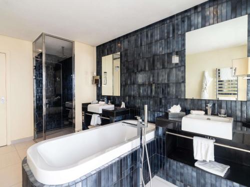 a bathroom with a bath tub and two sinks at Sofitel Casablanca Tour Blanche in Casablanca