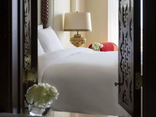 a bedroom with a white bed with a lamp and flowers at Sofitel Bahrain Zallaq Thalassa Sea & Spa in Manama