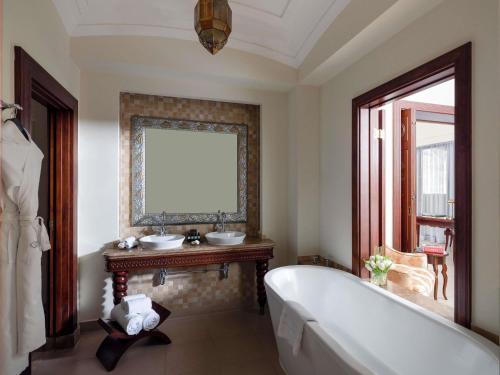 a bathroom with a tub and two sinks and a window at Sofitel Bahrain Zallaq Thalassa Sea & Spa in Manama