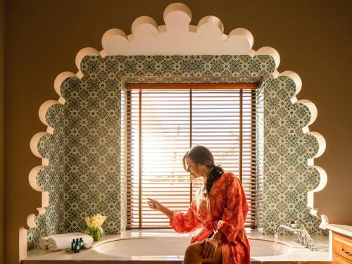 a woman sitting in a bath tub looking at her cell phone at Sofitel Bahrain Zallaq Thalassa Sea & Spa in Manama