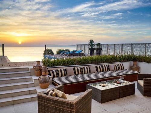 a patio with a couch and chairs and the ocean at Sofitel Bahrain Zallaq Thalassa Sea & Spa in Manama