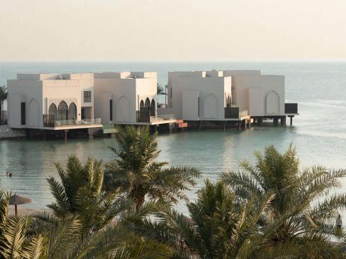 a house on the water next to the ocean at Sofitel Bahrain Zallaq Thalassa Sea & Spa in Manama