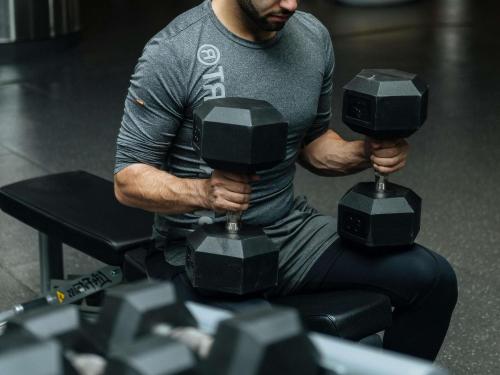 a man holding two large dumbbells in his hands at Sofitel Bahrain Zallaq Thalassa Sea & Spa in Manama