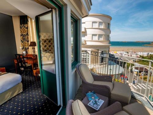 a room with a balcony with a view of the beach at Royal Emeraude Hotel Dinard - MGallery Collection in Dinard
