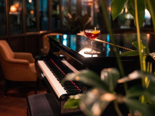 a wine glass sitting next to a piano with a drink at Royal Emeraude Hotel Dinard - MGallery Collection in Dinard