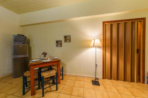 a room with a table and a refrigerator and a lamp at Grekis Beach Hotel and Apartments in Petalidhion