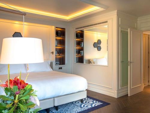 a bedroom with a bed with a lamp and a window at Sofitel Barcelona Skipper in Barcelona