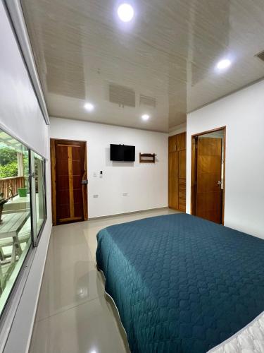 a bedroom with a blue bed and a tv at KETHALYA TAYRONA Hostal in El Zaino