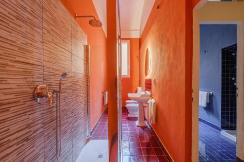 un bagno arancione con due bagni e una doccia di Unique Bologna Penthouse with Frescoes and Charm a Bologna