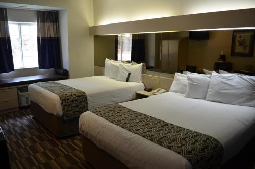 a hotel room with two beds and a mirror at Stay Express inn and Suites Atlanta Union City in Union City