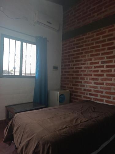 a bedroom with a bed and a brick wall at Cabañas Boutique NanakaUta in El Ceibal